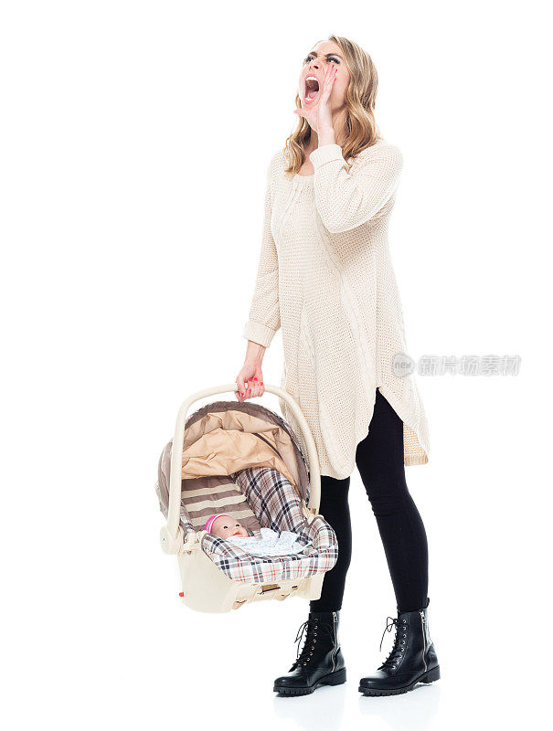 年轻漂亮的妈妈穿着一件毛衣抱着一个婴儿汽车座椅大叫