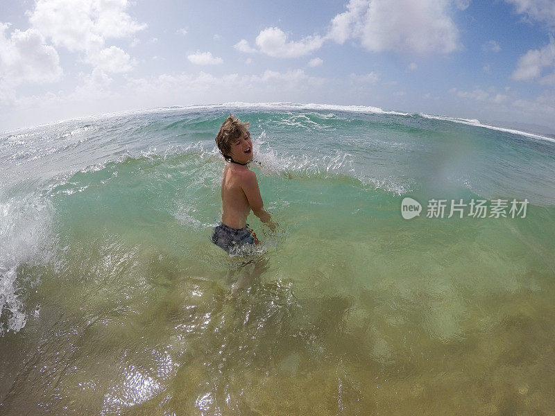 小男孩在夏威夷考艾岛玩，溅水，享受美丽的海水。