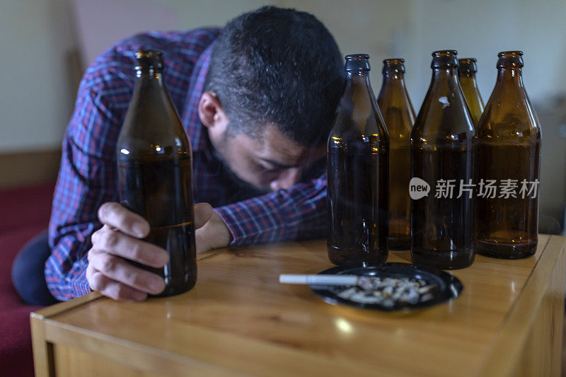 年轻悲伤的醉酒男子喝啤酒和酒精感到浪费，孤独和绝望的痛苦和情绪压力。人与酗酒、上瘾和男人抑郁的概念。