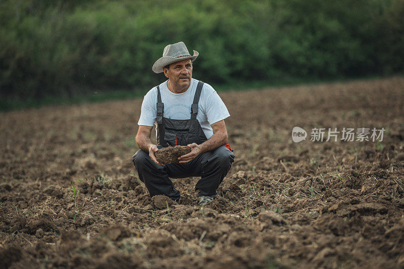 农夫在他的土地上看着土壤