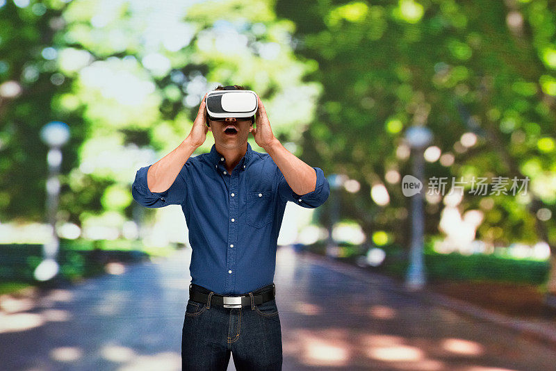 白种年轻男性站在公园前使用虚拟现实模拟器