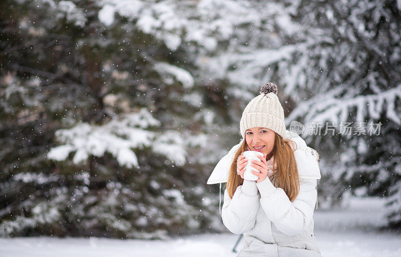 年轻女子喝着咖啡，热巧克力，茶，外面是雪