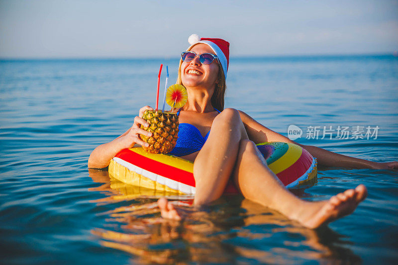 年轻女子浮在水面，喝着鸡尾酒