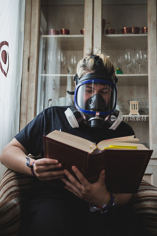 年轻女子戴着面具在家看书。