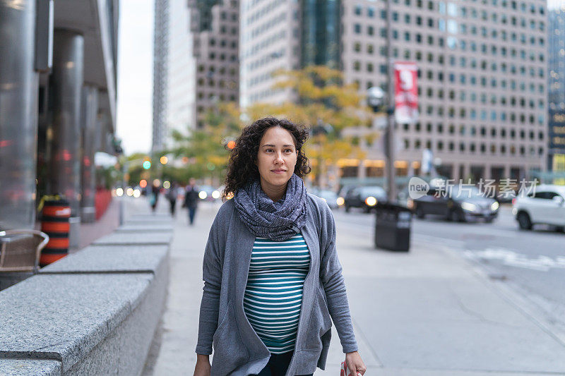 孕妇走在城市的人行道上