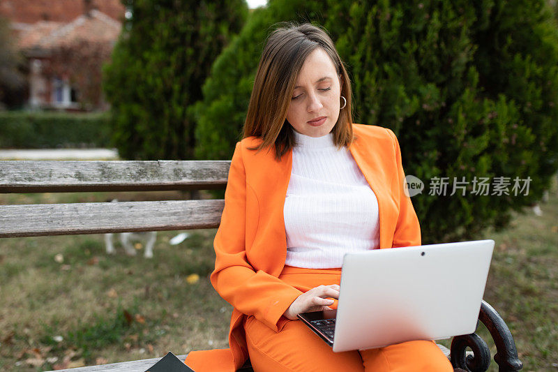 一位年轻女子在公园里用笔记本电脑工作