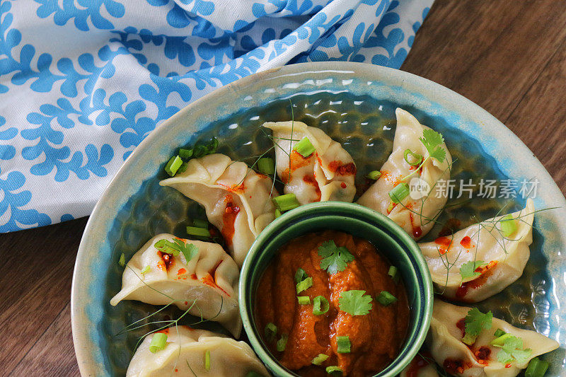 以茶巾为背景的蒸馍馍(南亚饺子)，白面和水面团填满鸡肉，混合蔬菜，淋上辣椒油，点缀葱花，茴香，香菜叶，特写