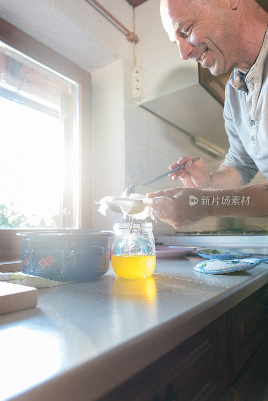 男人在家庭厨房柜台与精度过滤泡沫从融化黄油，以使一个完美的酥油