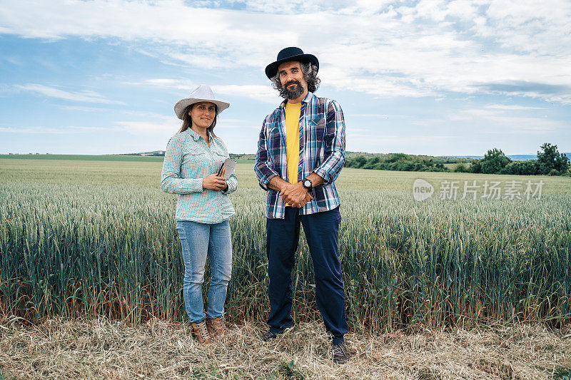 一个农民的家庭站在麦田中间，微笑着看着镜头。农业职业。家族企业。