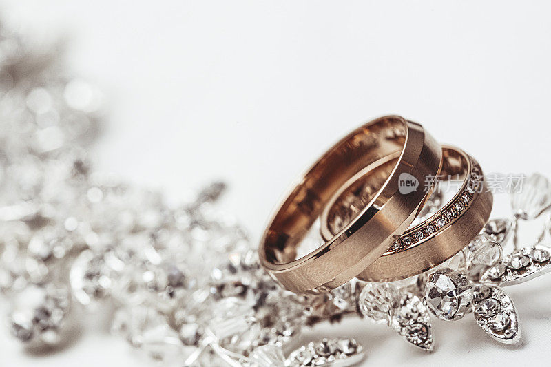 一对结婚戒指，镶嵌在奢华的珠宝上，以白色为背景