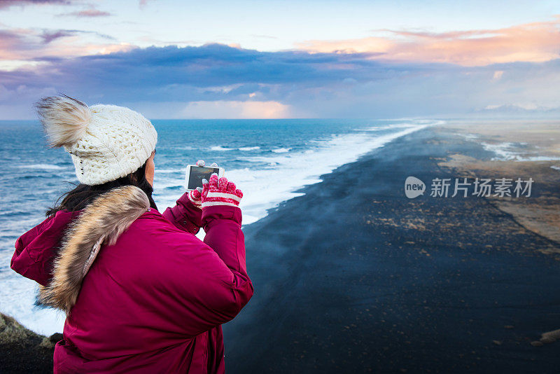 一名女子在冰岛南部的维克附近拍摄著名的黑沙滩