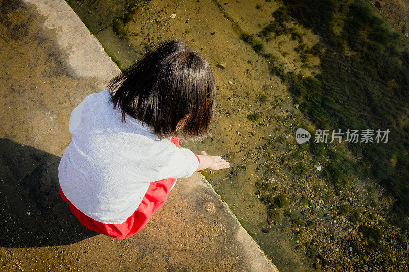 一个中国女孩在河岸上玩水