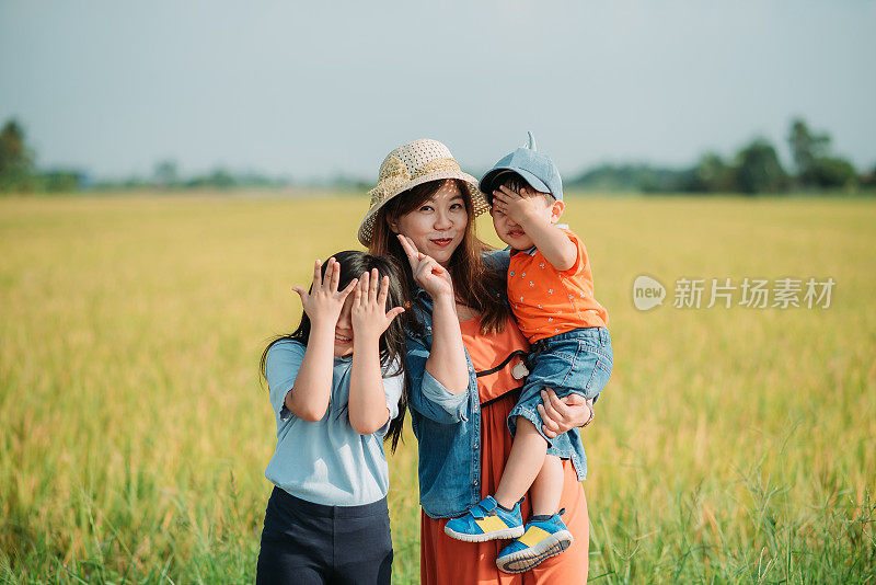微笑的亚洲华人家庭与孩子们在稻田里度过闲暇时光
