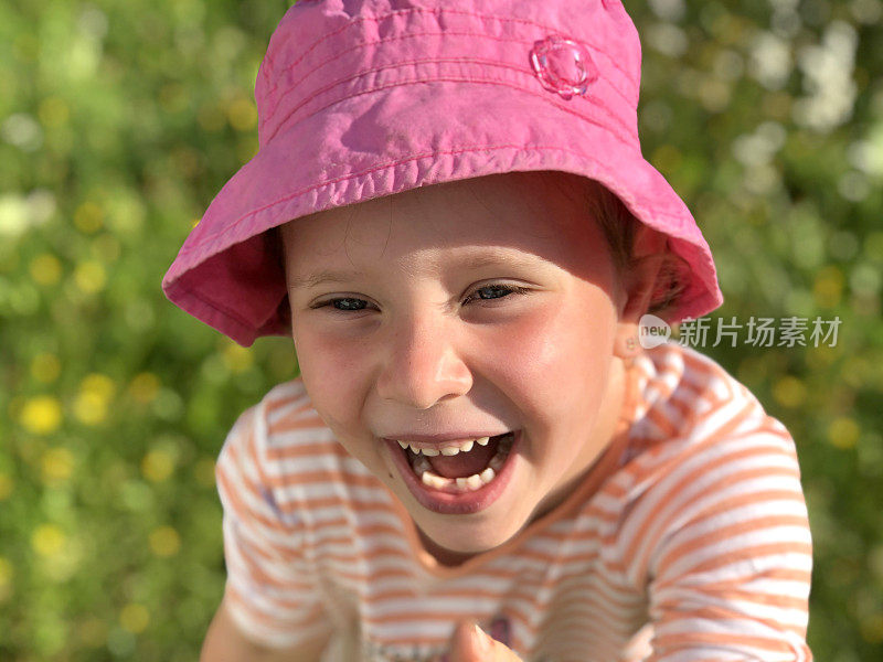 一个五岁白人女孩的肖像。女孩笑得很开心。夏天阳光灿烂的日子。