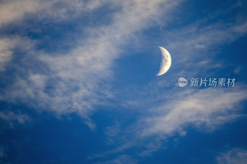 半月形的月亮是在白天，在蓝色的天空和缕缕的云