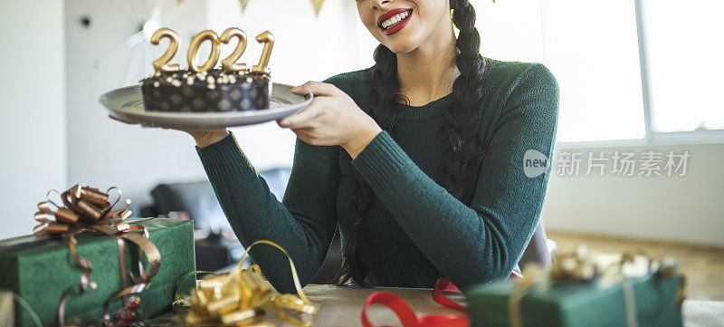 年轻女子准备新年派对的特写，包装礼物和在家做巧克力蛋糕