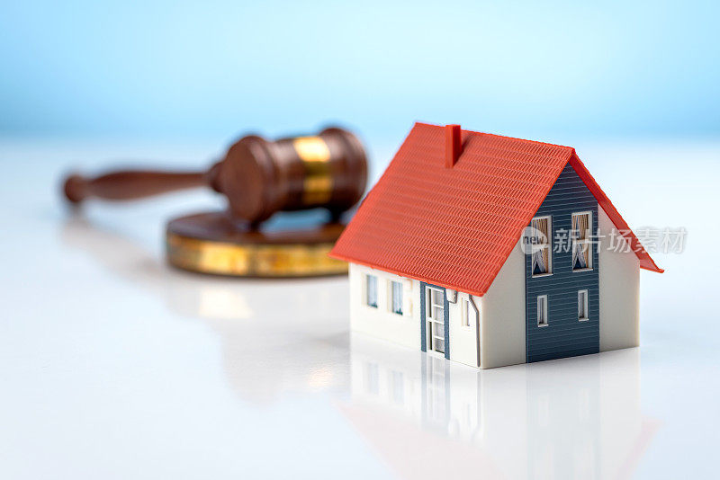 房地产法律和房屋拍卖的概念。法官的铁锤和蓝色背景下的房子。