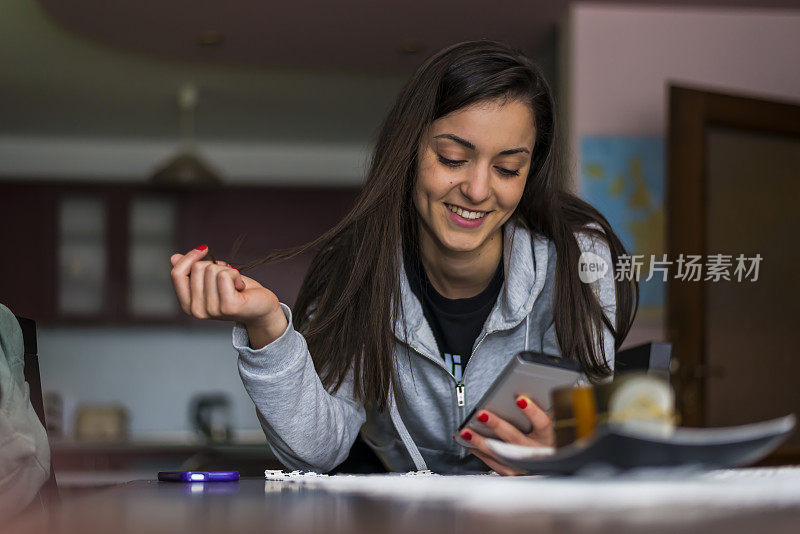 一个十几岁的女孩在家里使用电话和上网。