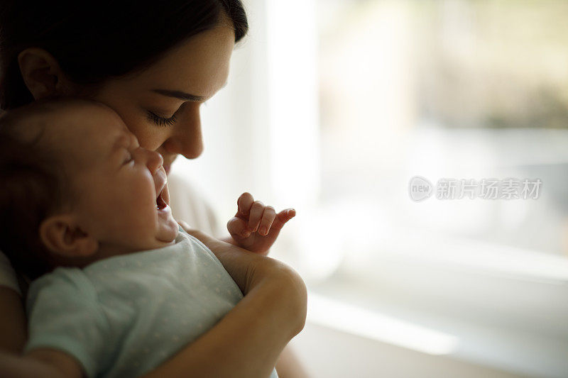新生婴儿在妈妈的手中哭泣