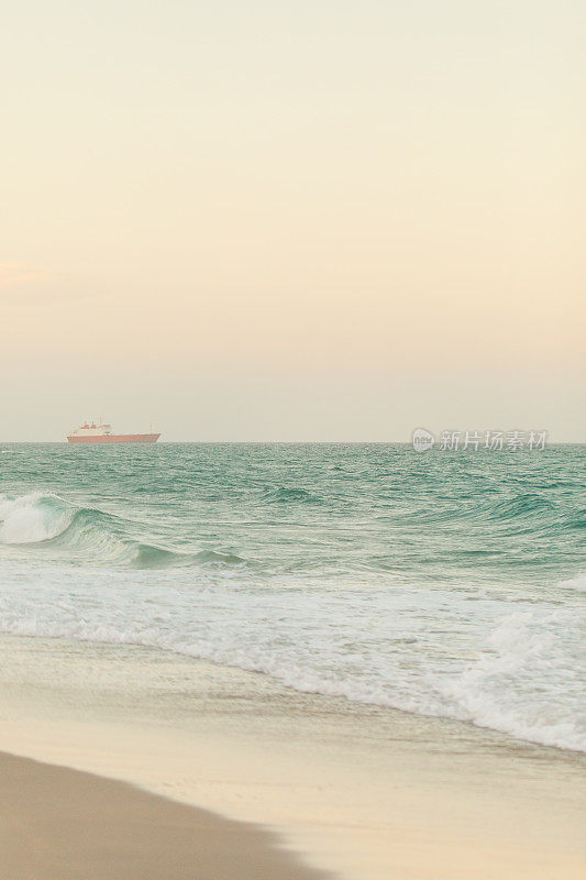 在佛罗里达棕榈滩的海岸线上的蓝绿色海浪上的柔和的日落