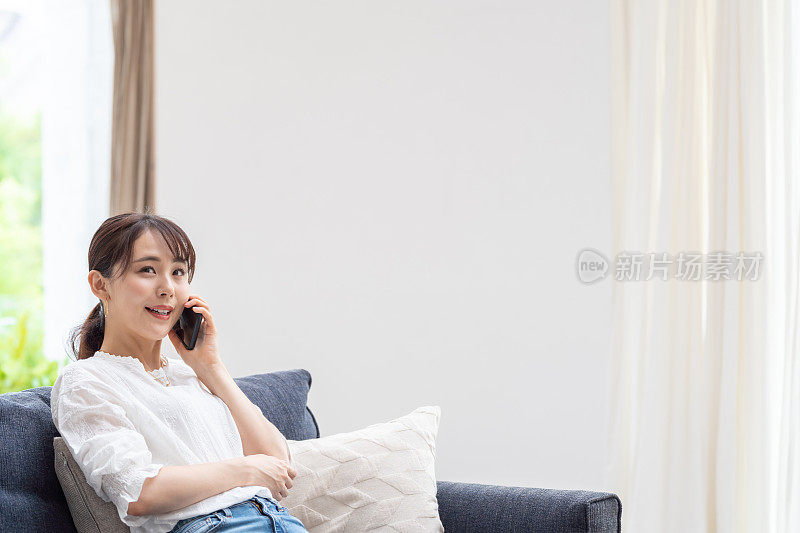 迷人的日本女人在客厅使用智能手机