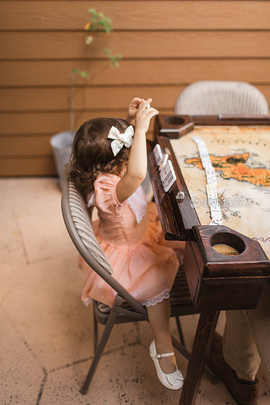 COVID-19期间，一个半古巴半高加索的小女孩在家里的简单的2岁生日派对上玩多米诺骨牌