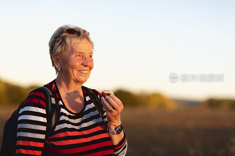 一位老妇人在远足时吃苹果