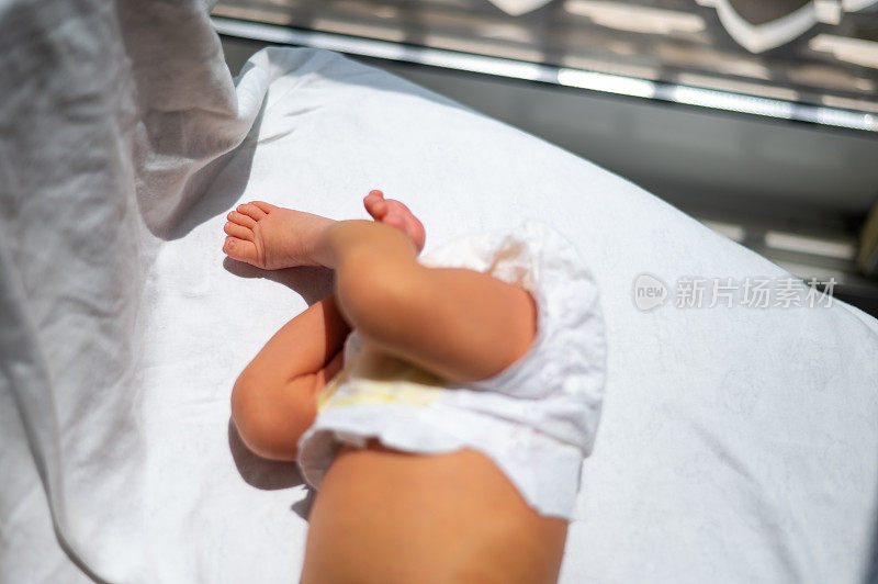 新生儿男婴靠窗吸收阳光，在家裹着毯子治疗黄疸