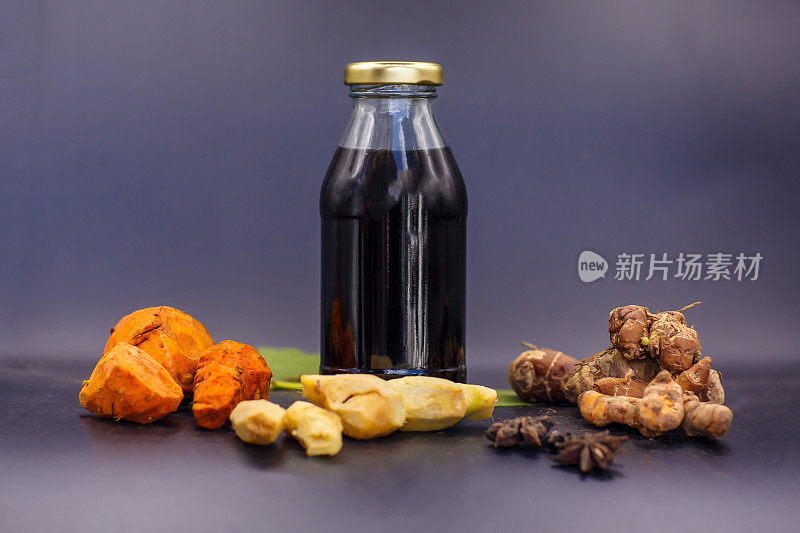 贾木-印度尼西亚草本饮料在玻璃瓶中与天然成分:姜黄，生姜，罗角和棕榈糖在灰色的背景。健康的生活方式