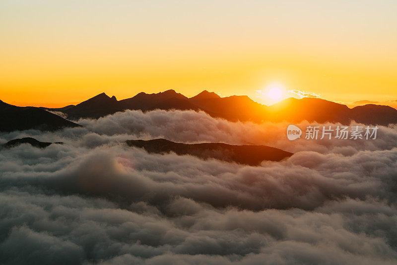 塔特拉山脉和黄色日落的秋景。云朵飘浮于山峰之上