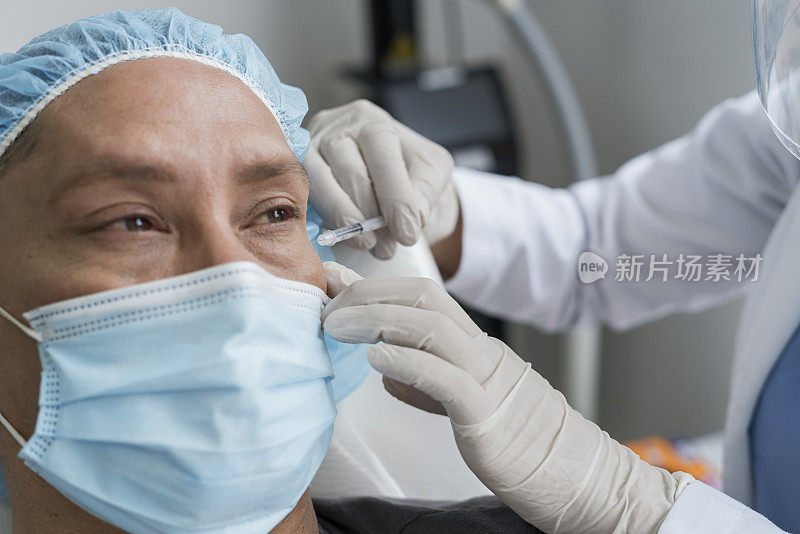 一名男子躺在轮床上，通过戴着口罩的医生在脸上注射肉毒杆菌