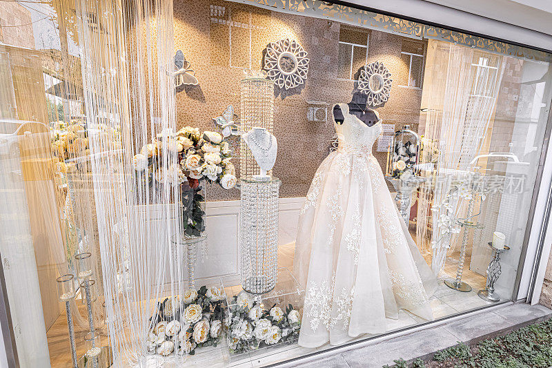 一个豪华婚礼沙龙的橱窗，展示着昂贵的缎子和面纱