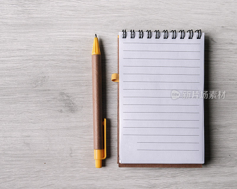 空白衬里记事本的再生纸与钢笔，白色的木材背景