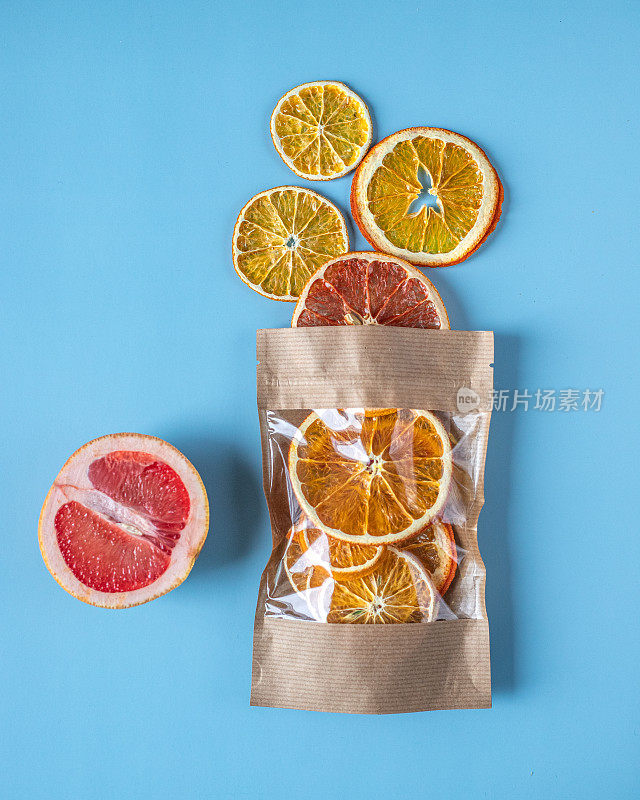 用蓝色背景的成熟葡萄柚，配上一个装着柚子、柠檬、橘子、橙子等干柑橘类水果的工艺包