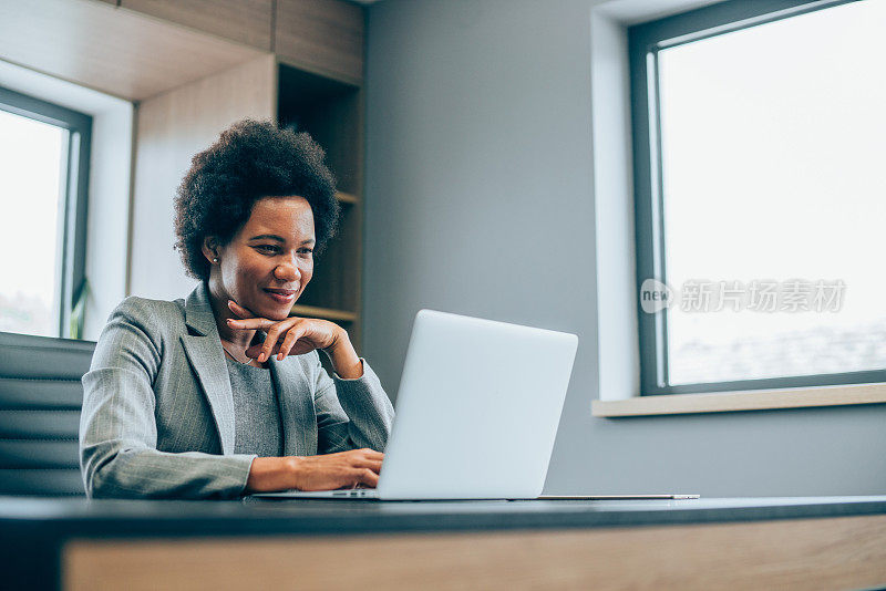 成功的女商人在现代办公室用笔记本电脑工作。