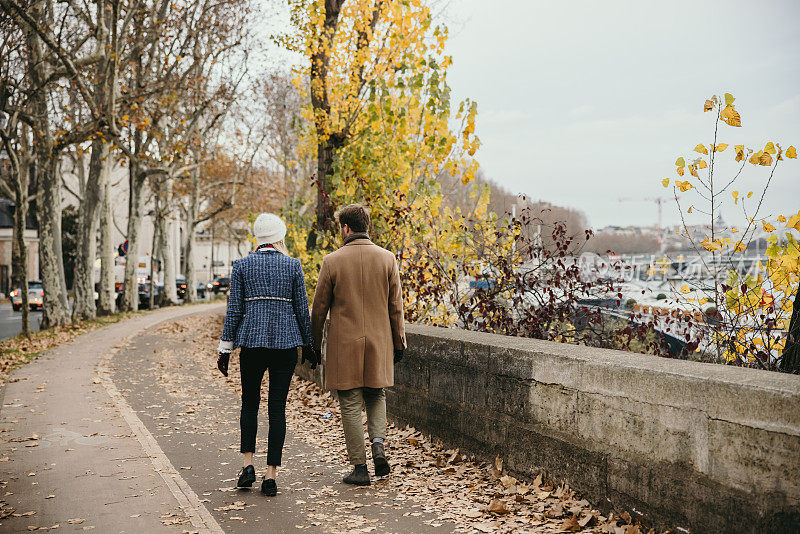 在巴黎塞纳河上，情侣们穿着冬装，手牵着手散步，后视镜