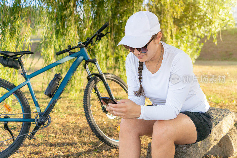 女孩在骑自行车锻炼后用手机查看社交媒体