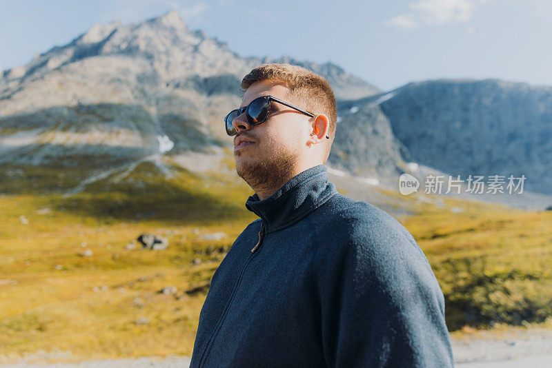 在阳光明媚的秋日里，一个人在挪威的山上徒步旅行