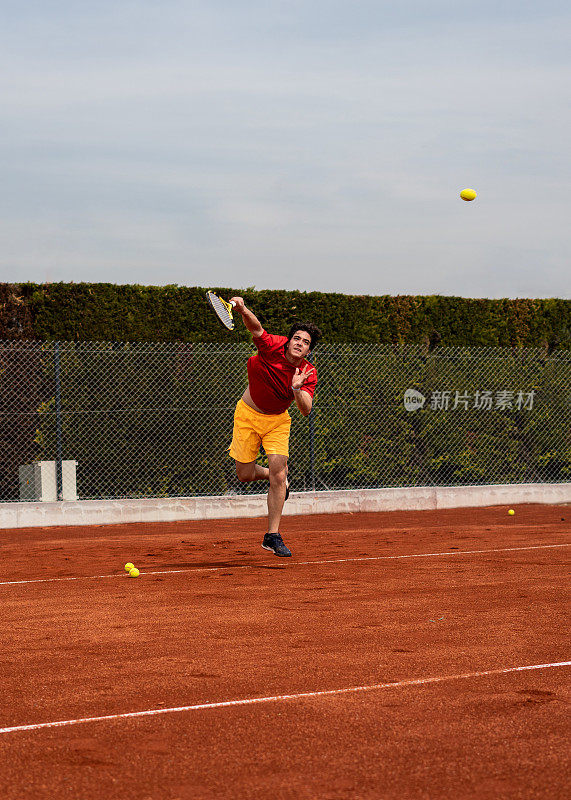 男子网球运动员仍然在红土球场打垂直网球