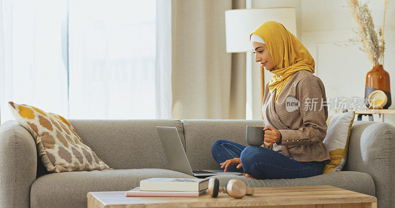 自由职业，穆斯林妇女坐在沙发上用笔记本电脑或在客厅在线输入电子邮件。年轻的阿拉伯学生在休息室放松，在家学习技术或在迪拜的沙发上学习研究