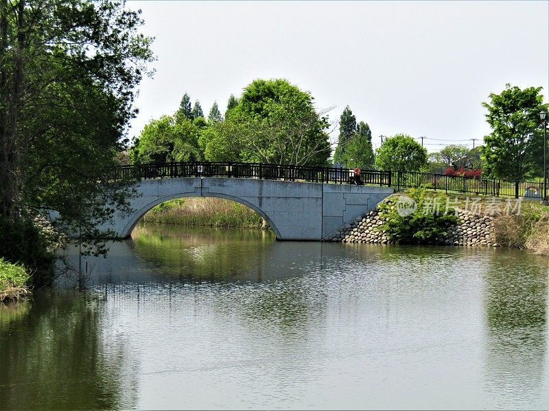 日本。4月。公园内的池塘和拱形人行桥。