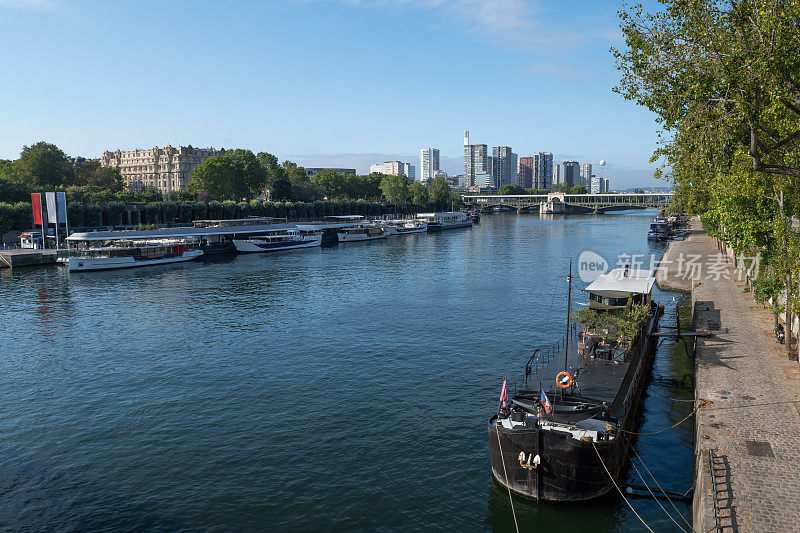 巴黎塞纳河，有海滨长廊，停泊的船只，热气球和现代办公楼