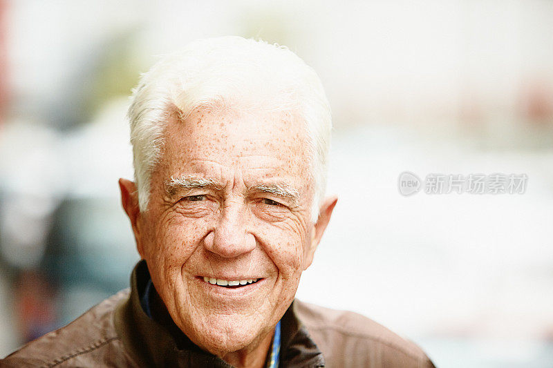 在城市街道上，一位英俊、微笑的老人