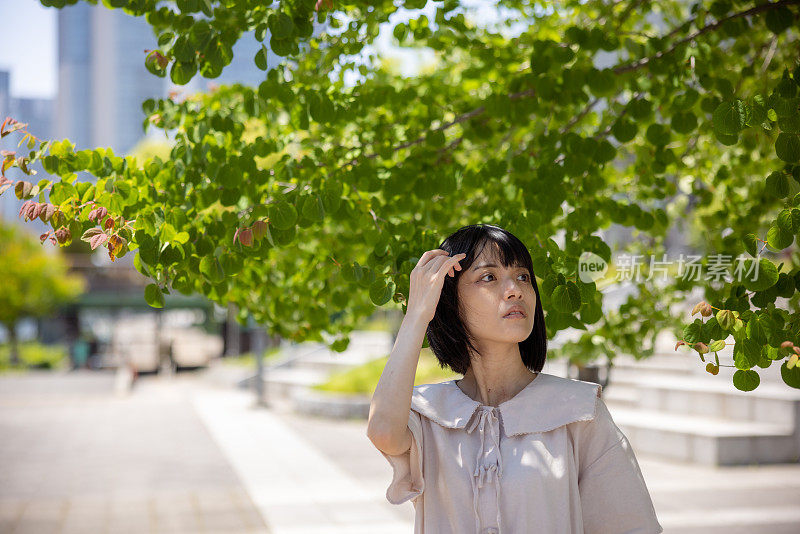 在城市的树下散步的女人