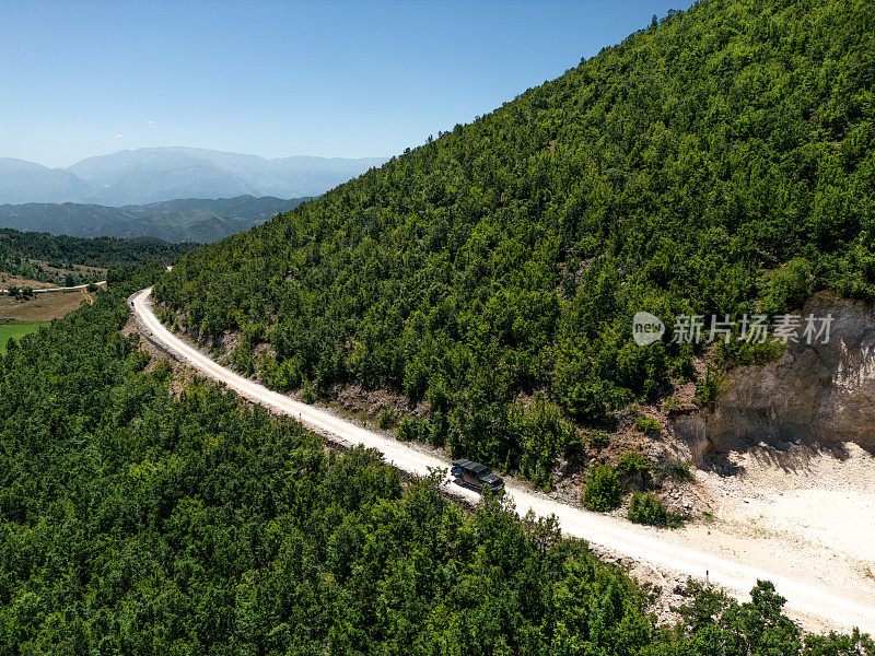 一辆越野车在山间森林中行驶的鸟瞰图