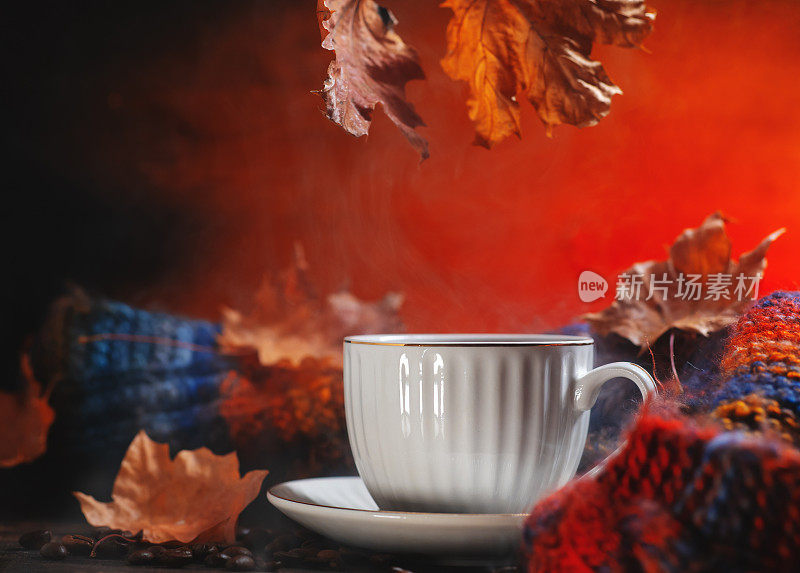 木桌上的一杯黑咖啡。秋天干枫叶和织围巾。桌上的咖啡豆