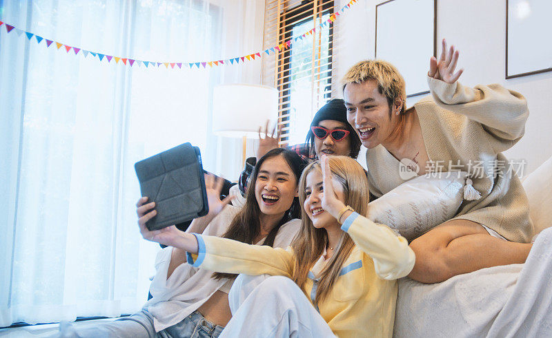 一群快乐的亚洲年轻人在家里用数码平板电脑和朋友视频通话。互联网通信信息技术，远程会议，或聚会生活理念