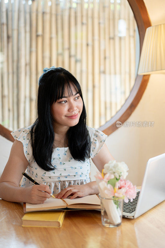 一个放松，美丽的亚洲女人是白日梦，而写她的日记在咖啡馆。