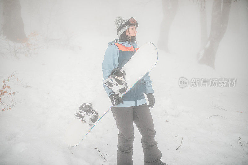 女子准备在山上骑滑雪板。她喜欢雪地活动和冬季运动