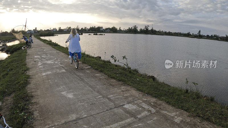 成熟的女人骑着自行车穿过稻田